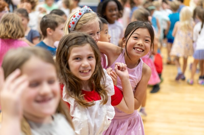 Two girls smile and pose in a crowd of students.